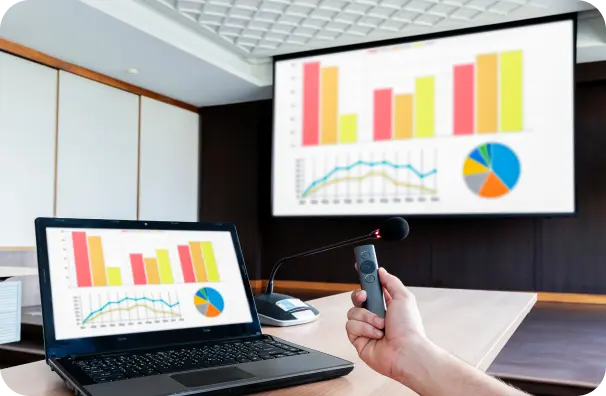 Imagem de laptop em mesa de reunião com tela de exibição de gráficos de desempenho ao fundo